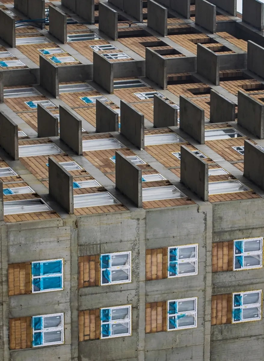 Unfinished apartment building facade with repeating balconies and blue-covered windows